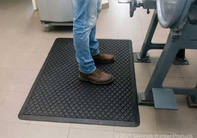 Factory worker standing on anti-fatigue safety mat in industrial setting