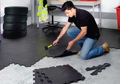 Close-up of rubber and PVC mats side by side in a UK workshop setting, highlighting texture and thickness differences