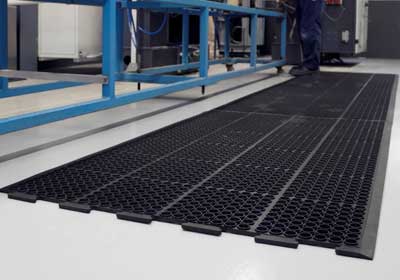 Close-up of heavy-duty rubber industrial mat in a UK warehouse setting, showing anti-slip surface texture